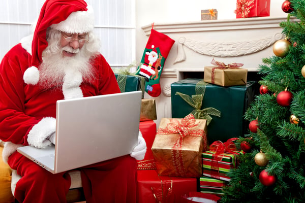 Santa Claus sitting next to a Christmas tree with a laptop-1